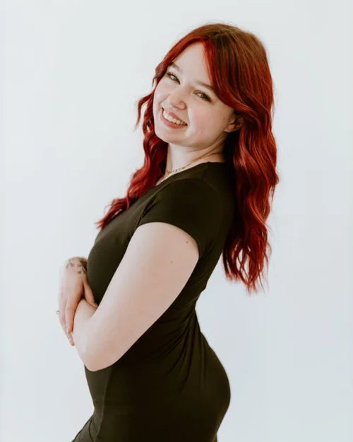 Woman with red hair wearing a black dress against a white background
