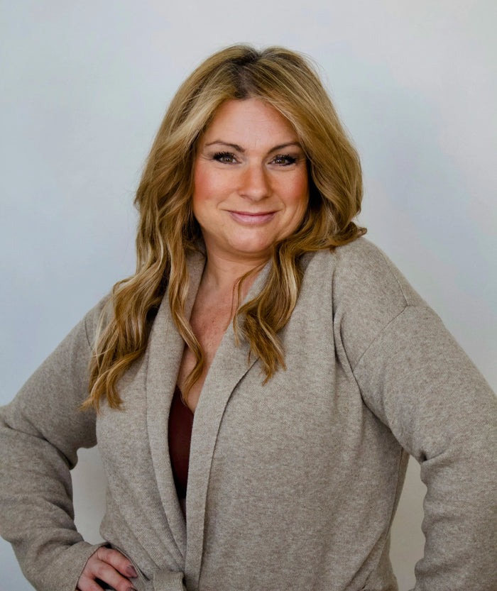 Woman wearing a beige cardigan against a plain background